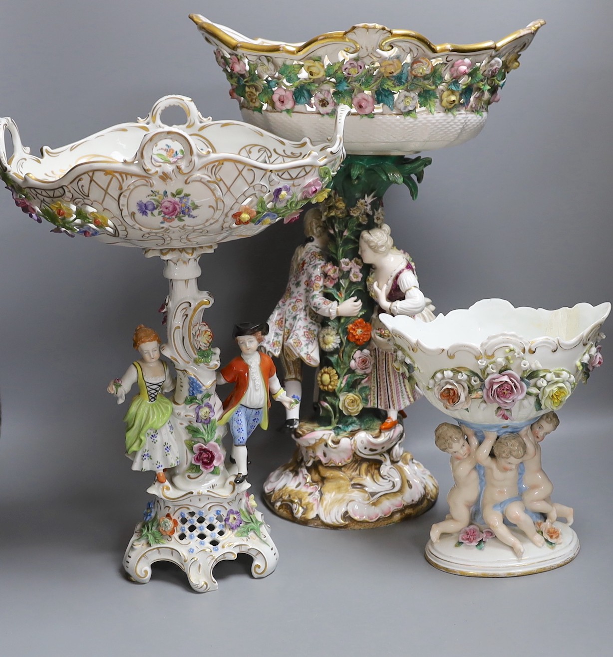 A 19th century Dresden floral encrusted centrepiece and two other continental porcelain centrepieces, tallest 46cm